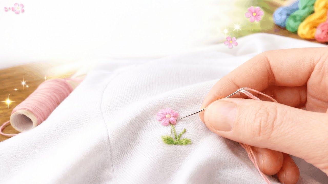 Hand embroidery needle stitching a pink flower on white fabric with silk thread detail