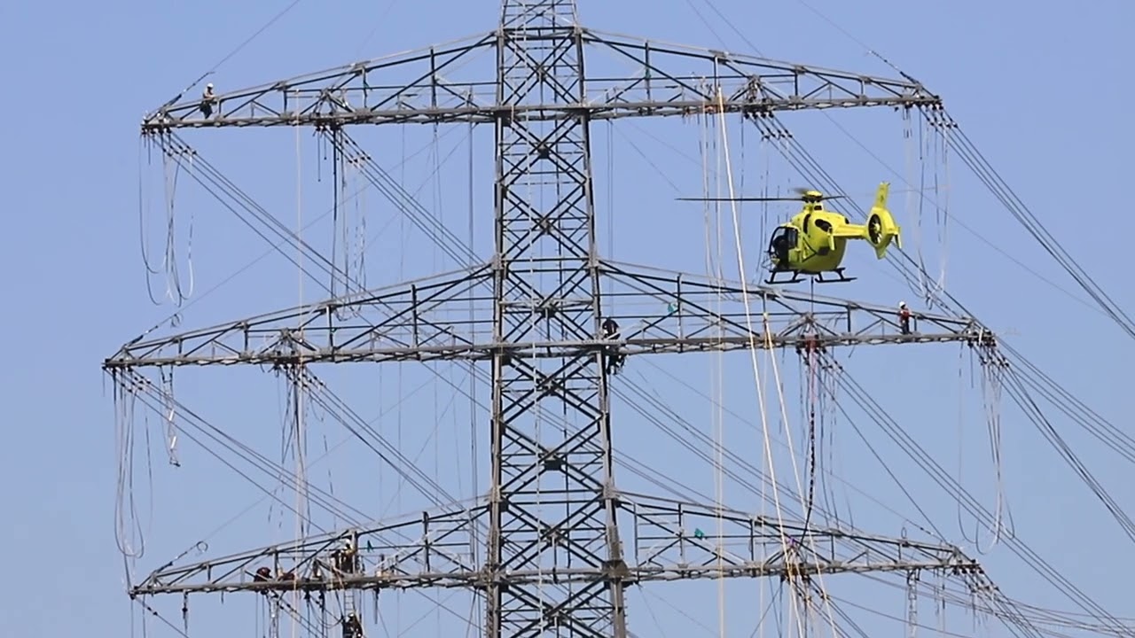 EC135 D-HHWK of Sky Heli pulling cables between the power poles.