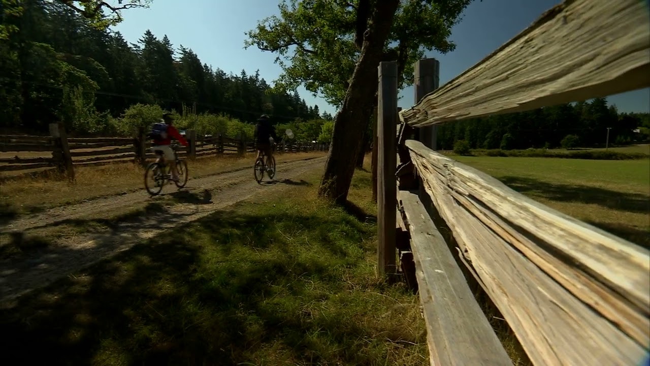 Salt Spring Island - Ruckle Park - Pan right to left from a fence to a couple biking