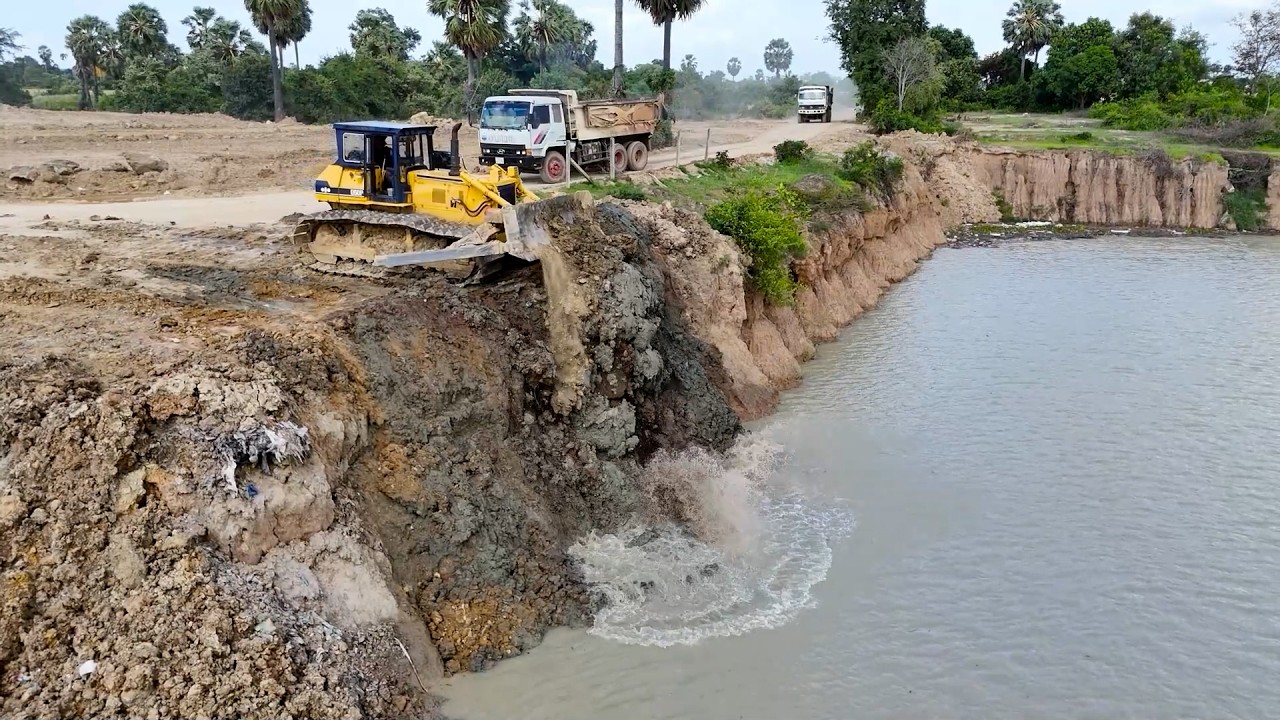 Large Processing Landfill into Deep Large Pond useTechnique Bulldozer Clearing Soil and Dump Truck