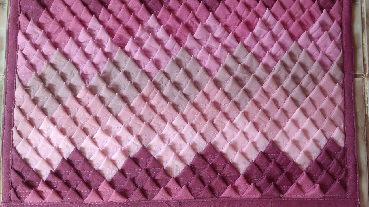 Tapete de retalhos em tecido, com bicos simples, formando losângulos em composê de cores