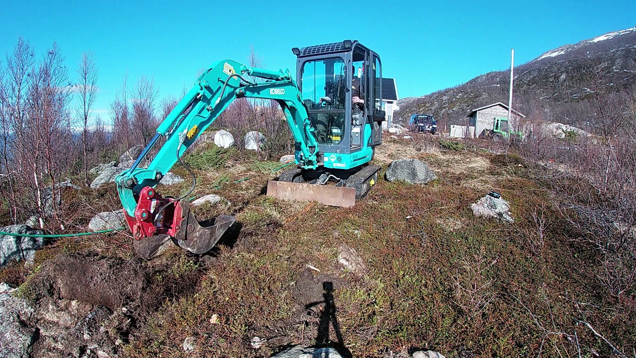 Mini excavator digging trench for main power to an cottage