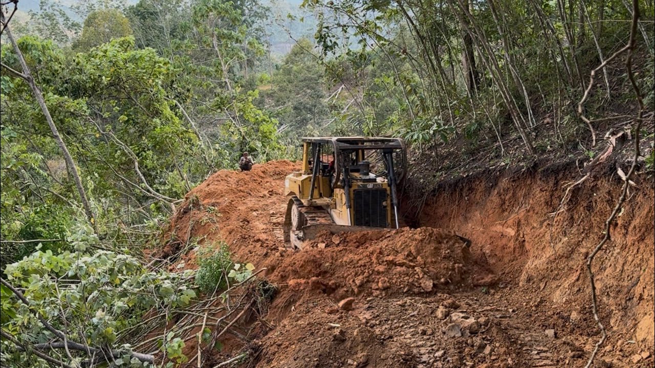 High Risk ! Bulldozer Operators push dirt on the edge of a cliff in the American Mountains.