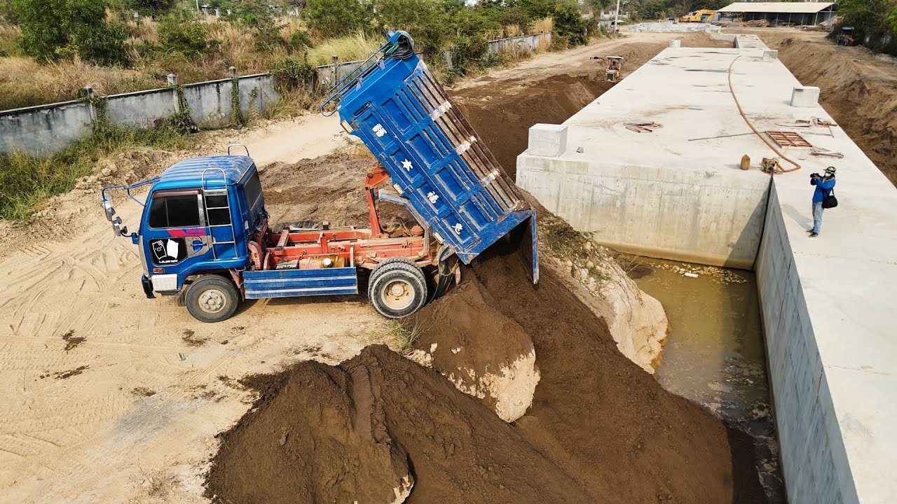 Underground Drainage Filling Cover By Sand Small Komatsu D30P Pushes Sand, Dump Truck Unloading Sand