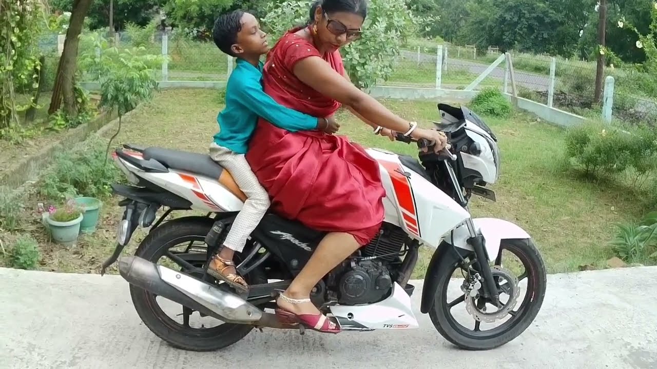 TVS Apache 180 cc bike riding wearing satin saree with a kid