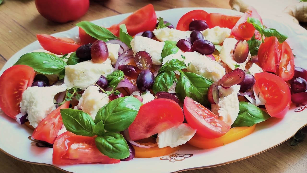 Kolorowe pomidory i ser mozzarella z winogronami. Klasyk w nowym wykonaniu