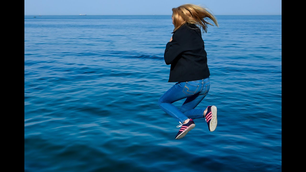 girl jumps from breakwater into sea water and then poses in wet clothes for wetlook video