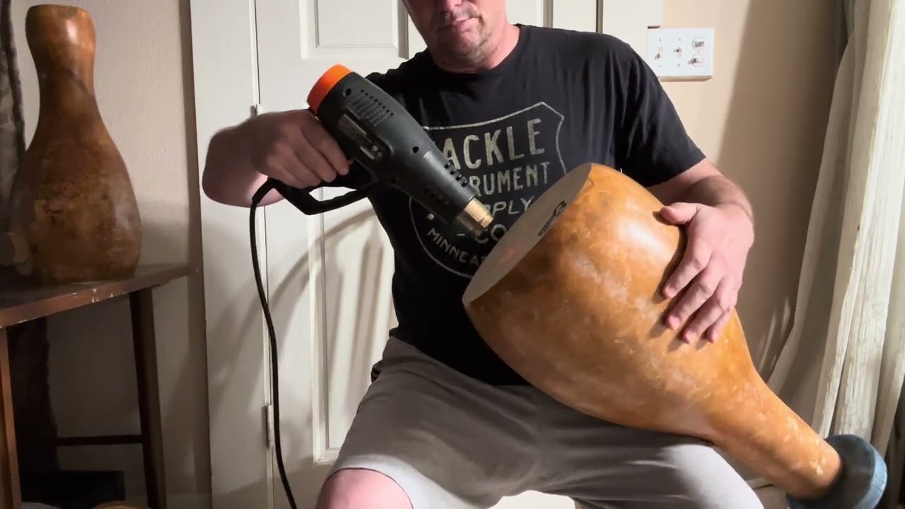 Re-Tensioning one of our headed gourd udu drums with a heat gun.