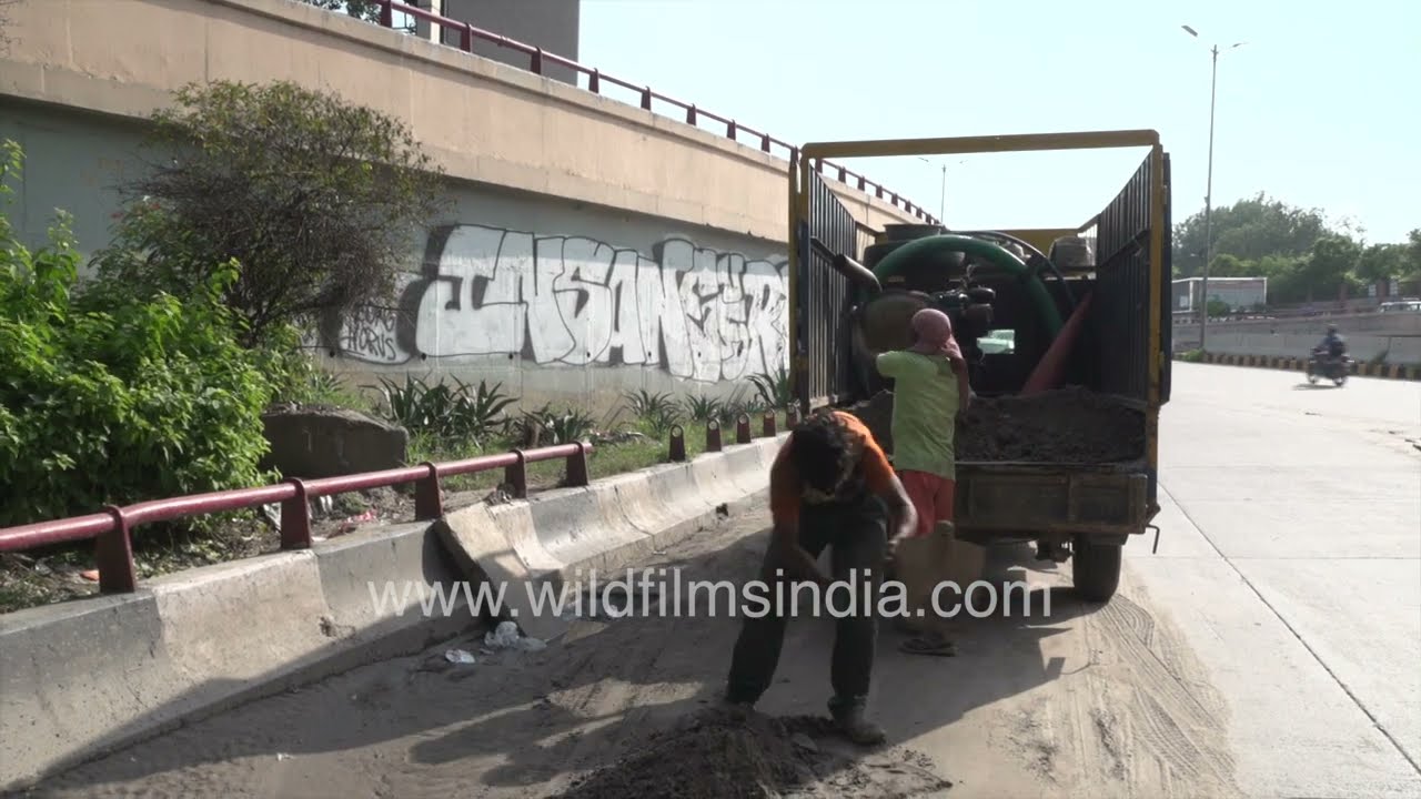 PWD workers work on road near Safdarjung Hospital, clearing monsoon malba to prevent drain blockage