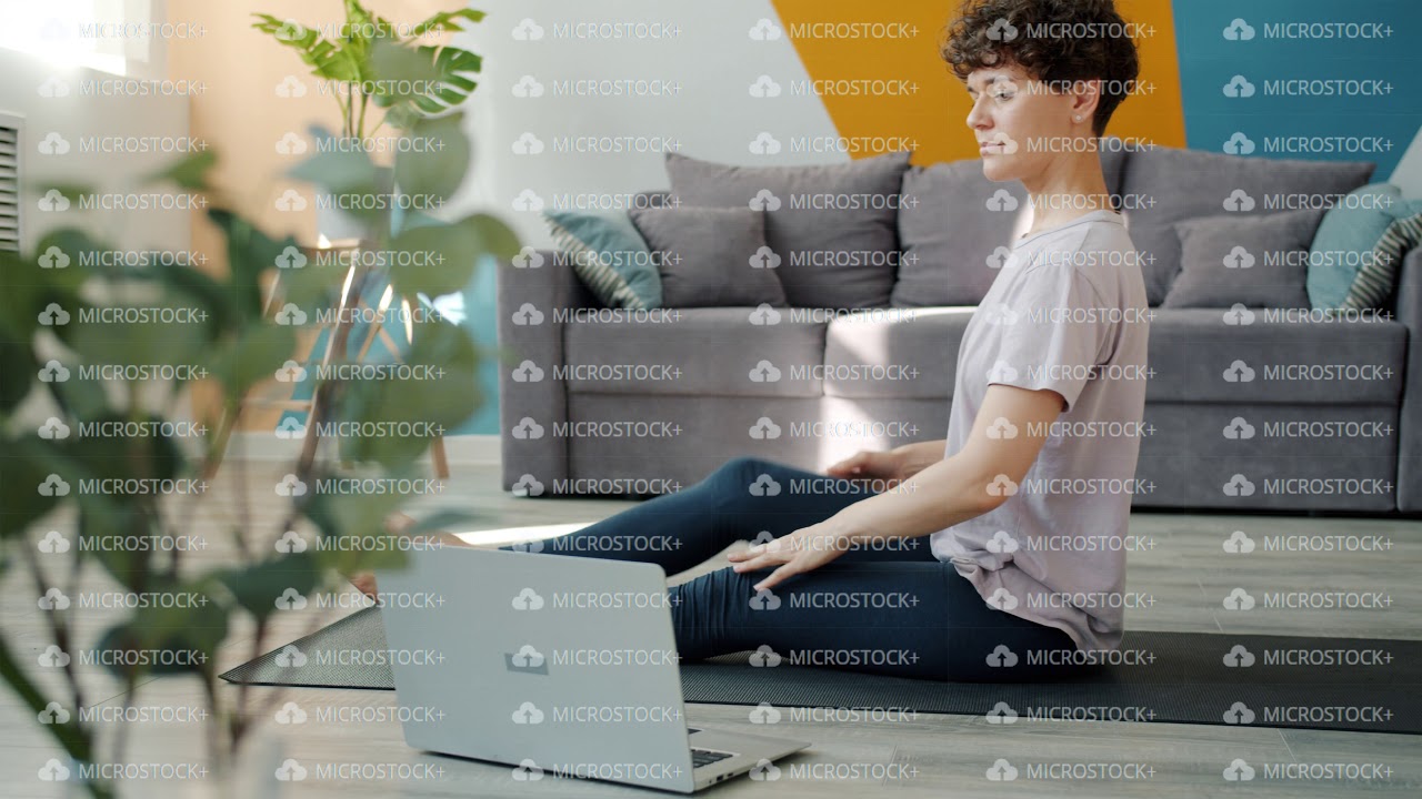 Flexible girl learning yoga online using laptop watching tutorial in internet