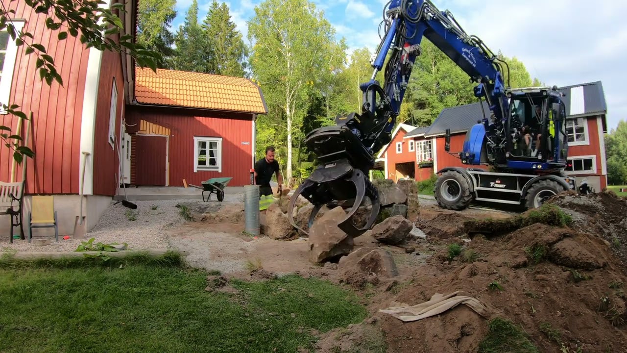 Bygger en stenmur med gr&auml;vmaskin