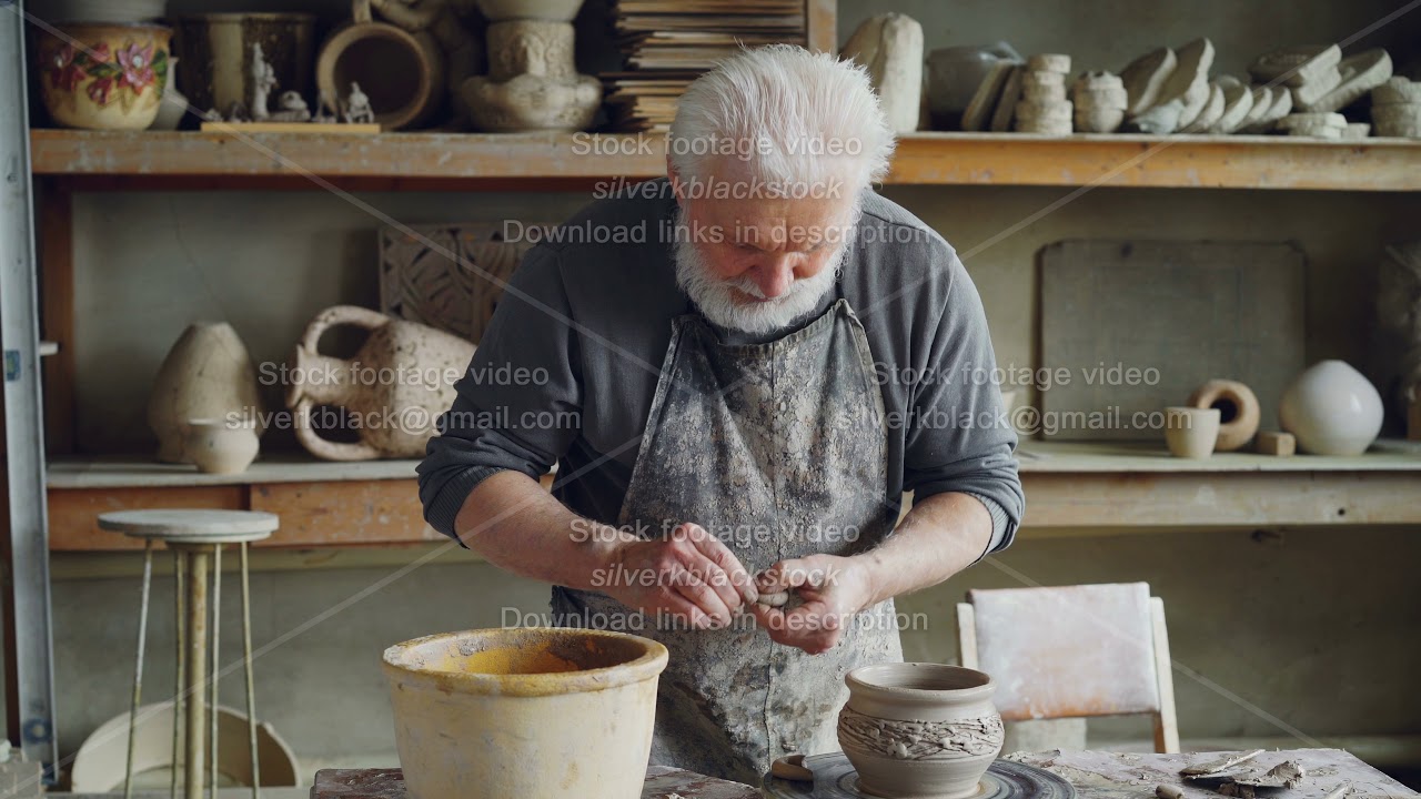 Experienced craftsman is making ear for ceramic bowl and fixing it on clayware while working in cozy