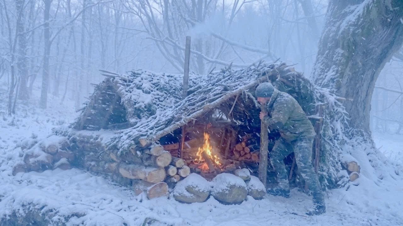 Bushcraft in a Snowstorm: Building a wilderness survival shelter from branches under a tree