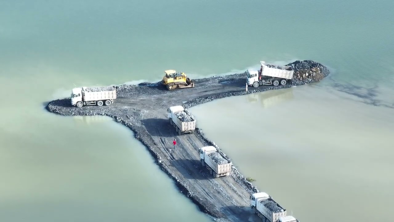 amazing stones are poured to build a road over water.dozer &Truck 25Ton , how much earth and
