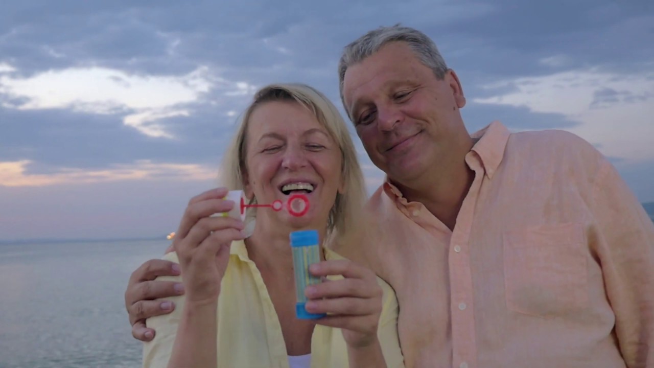 happy senior couple blowing bubbles on the beach QPYLW6U