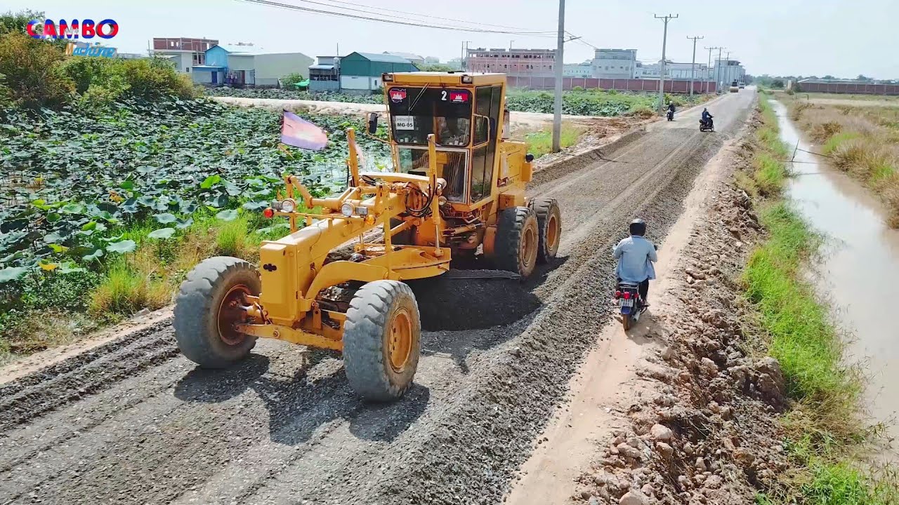 Great work! Motor Grader with dump truck Spreading Gravel building foundation for new Village Road