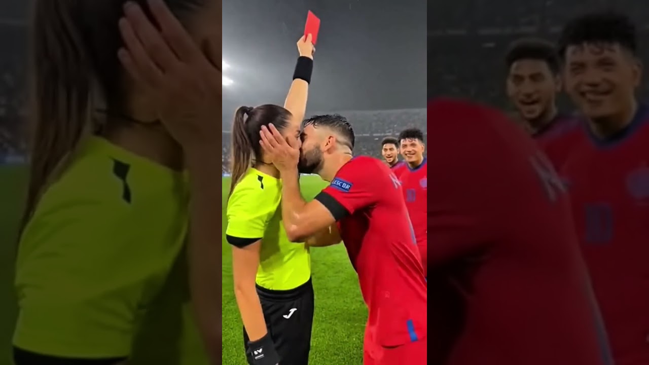 female referee halts the match and firmly raises a red card toward a male player