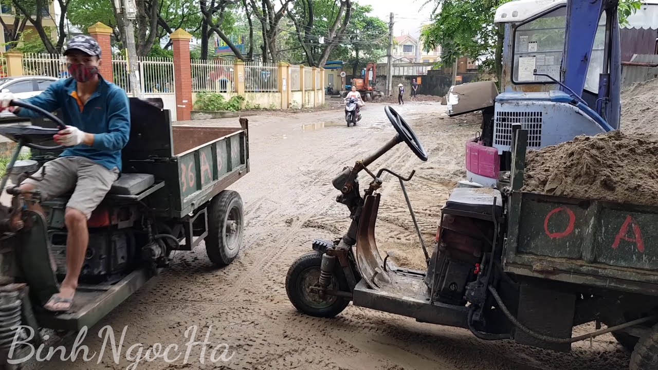 Three-wheeled tractor carrying construction materials