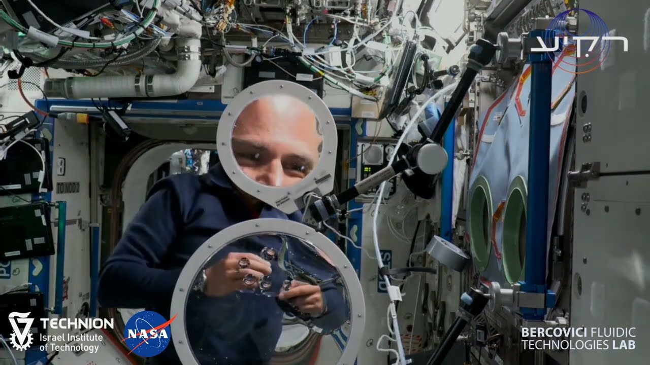 Astronauts Eytan Stibbe and Michael López-Alegría creating a large water lens on the ISS