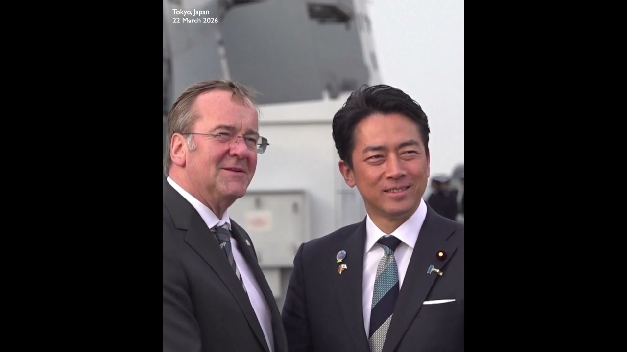 German and Japanese defense ministers shaking hands at Japan's naval base in Yokosuka