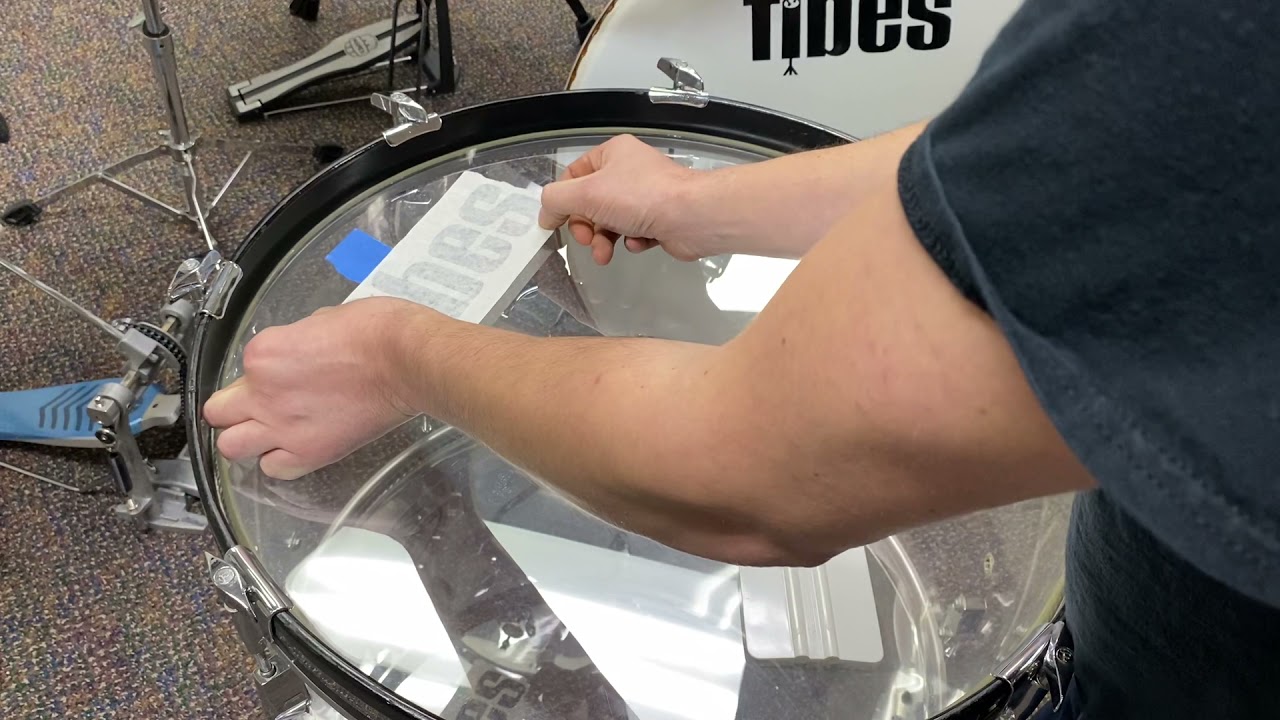Installing a vinyl logo on a drum head.
