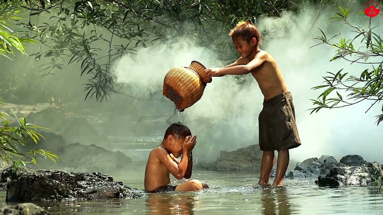 Asian boys having fun playing in the river with splashing water together