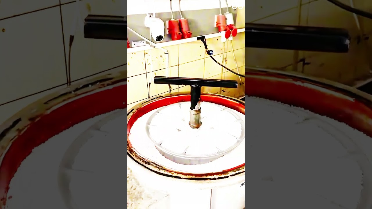 Polishing metal wheel rim in vibratory finishing machine with abrasive media.