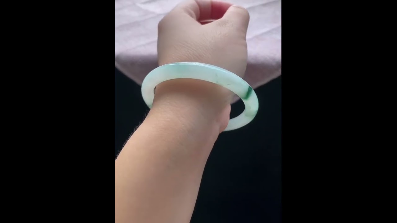 Round jade bracelet bangle with a smooth and lustrous texture and a floating flower pattern.