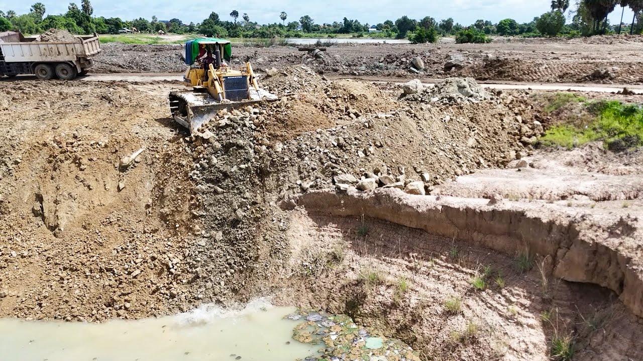 Strongly KOMATSU Bulldozer Push Soils Into Deeply Pond With Team Dump Trucks Supported