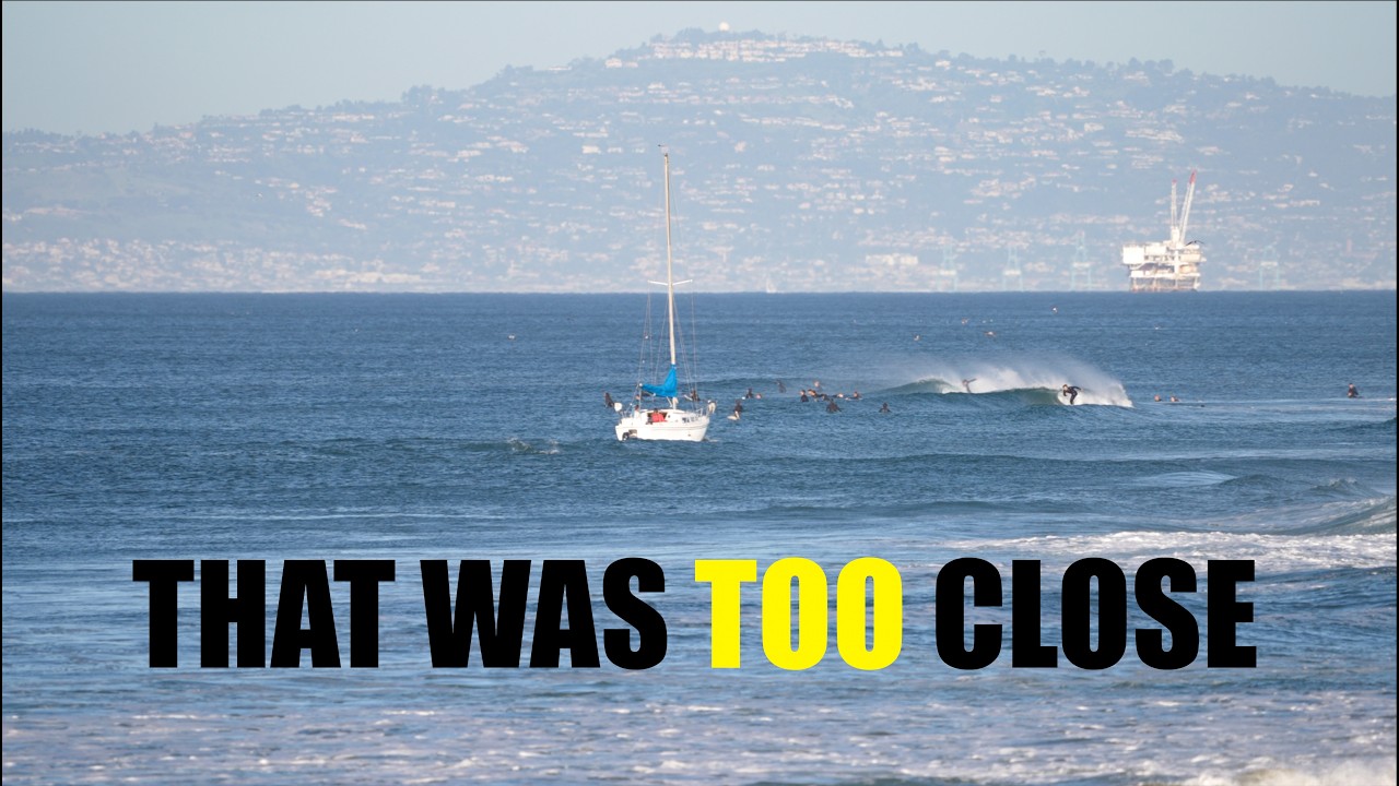 SAIL BOAT GOES CLOSE BY THE LINEUP IN NEWPORT BEACH