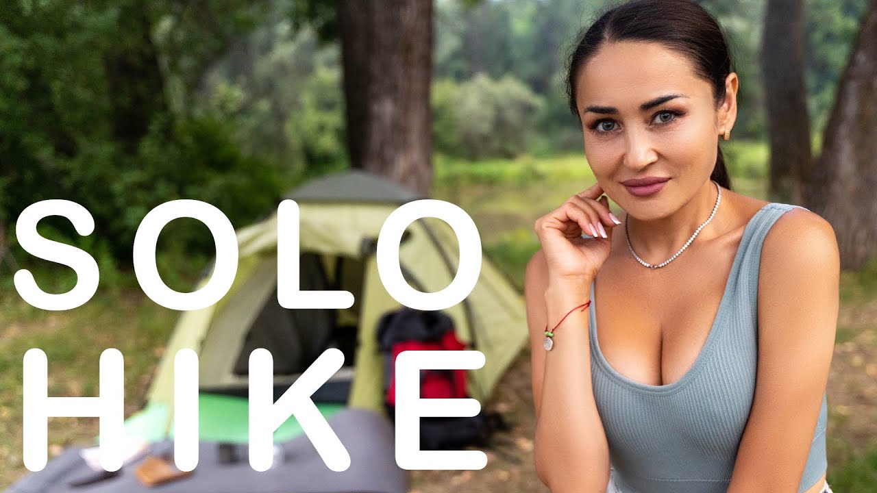 Girl hiking alone in summer forest.