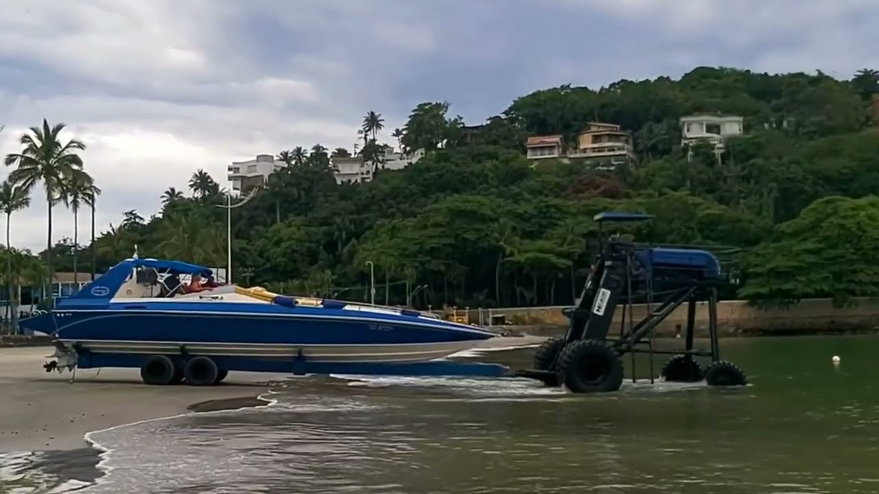 Trator gigante levando barco para dentro do mar. Guaruja praia da enseada. SP