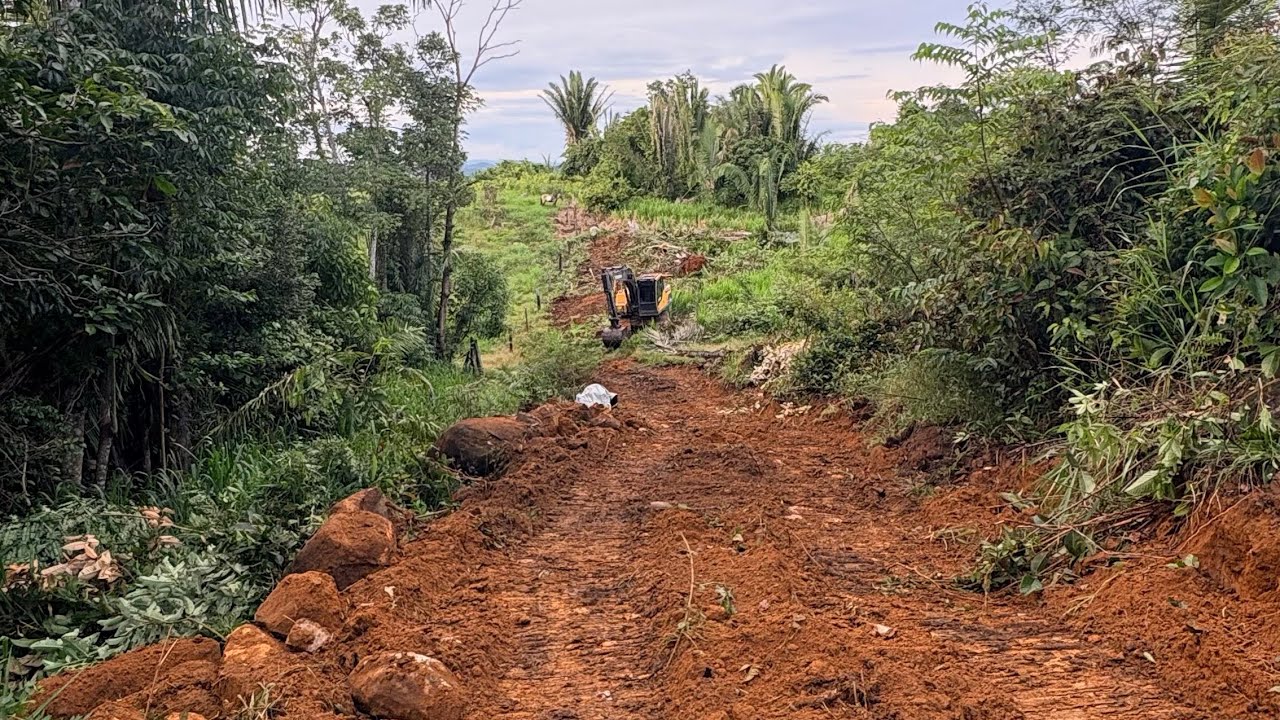 Escavadeira fazendo estrada em local de muita pedra 