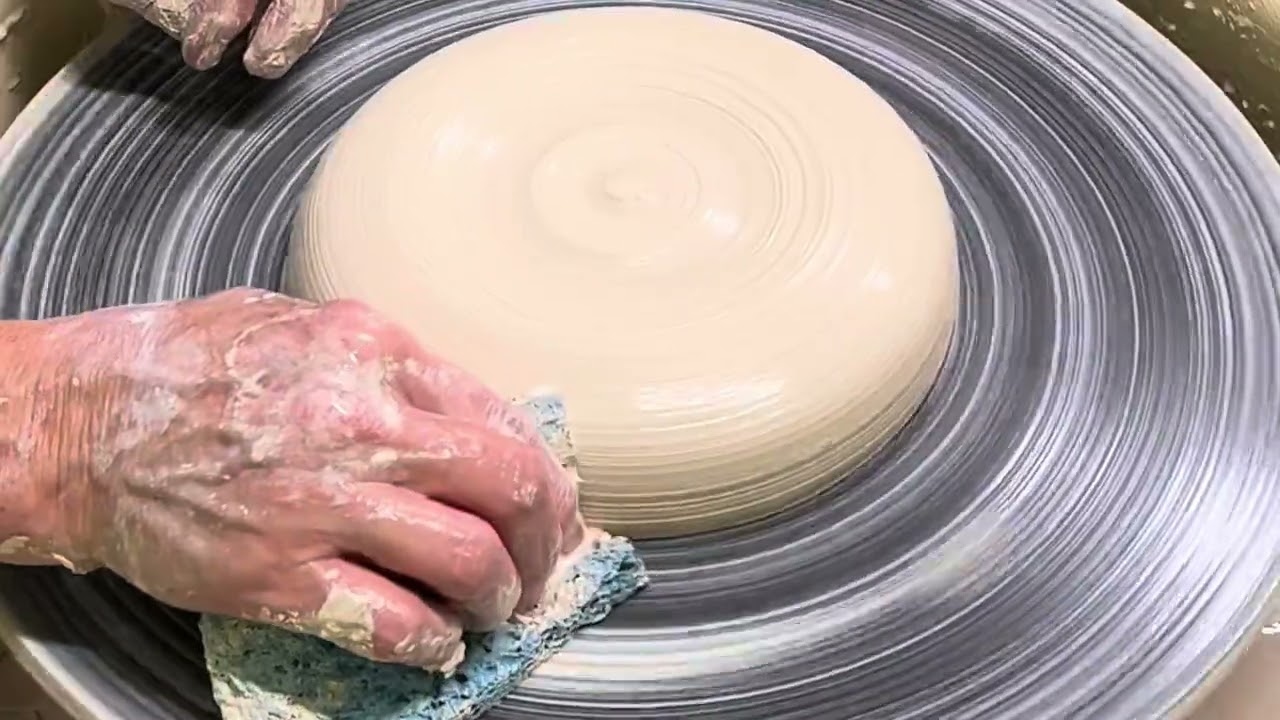 Wheel throwing a large rimmed pottery plate.