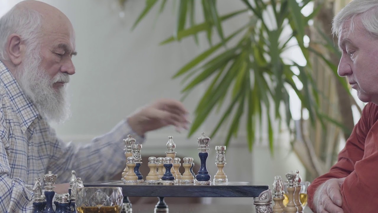 two old friends playing chess sitting at home caucasian old men