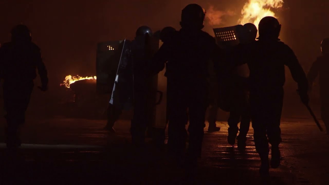 VideoVault Stock Video: Burning car during a riot police and rioters running