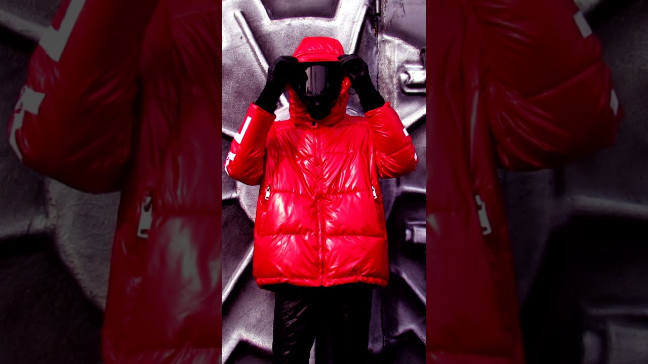 RED SHINE OVERSIZE DOWN JACKET WITH HOOD, LEATHER GLOVES AND LEATHER JEANS AND BLACK PANORAMIC MASK.