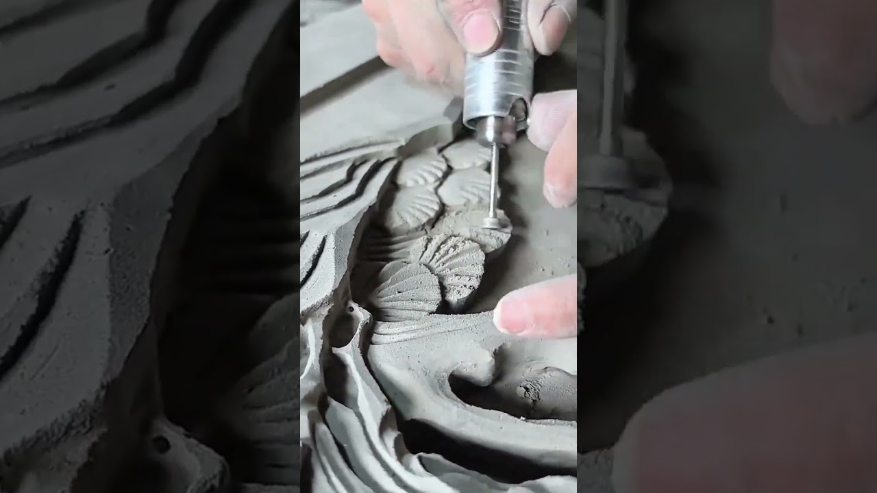 Master craftsman meticulously carves intricate floral details into damp clay surface