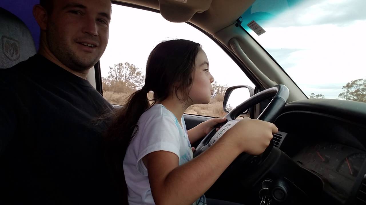 Daddy teaching his little girl how to drive.
