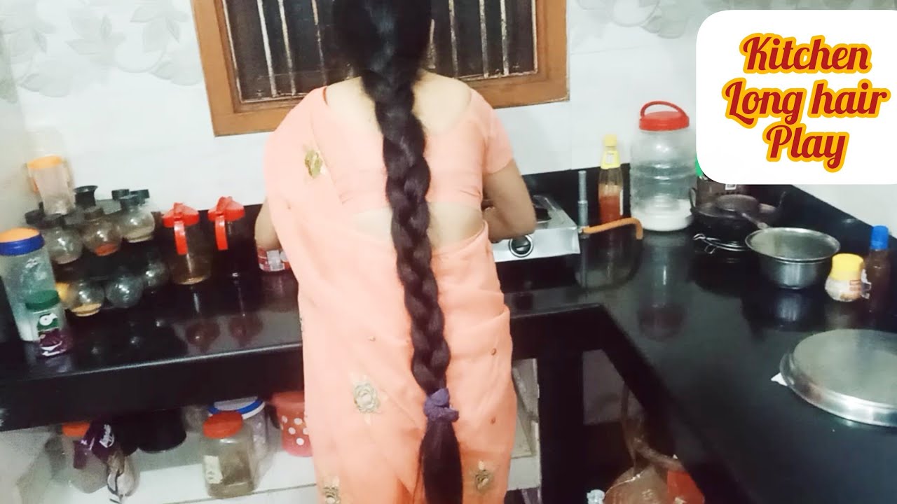Indian housewife with long hair braid working in kitchen 