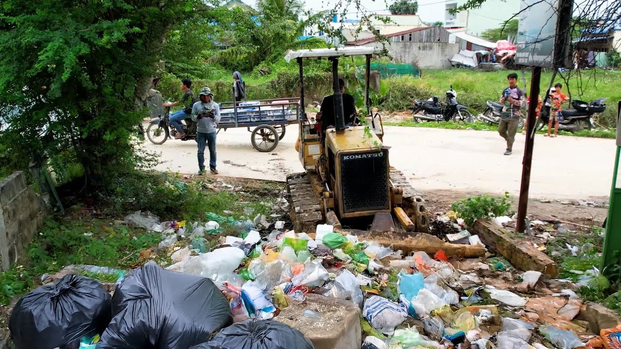 Bulldozer push the trash and then dump truck unload the stone for cover the trash