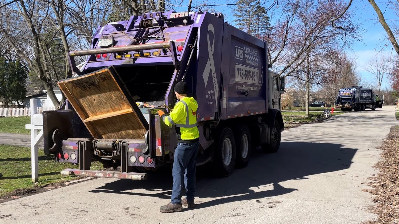 Two Rear Loader Garbage Trucks Packing Bulk on One Street: LRS Mack Heil 5000s