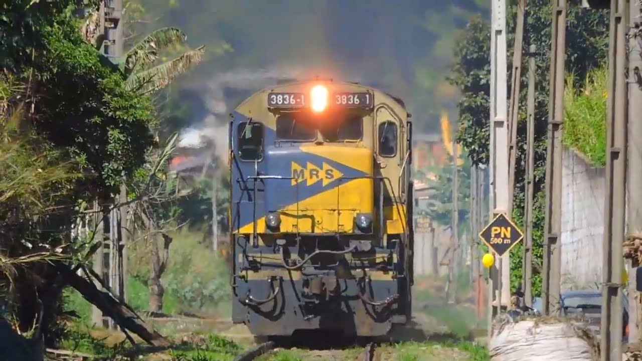 Dupla de locomotivas GE C36-7 acelerando forte na rampa com vagões plataformas na saída de Três Rios