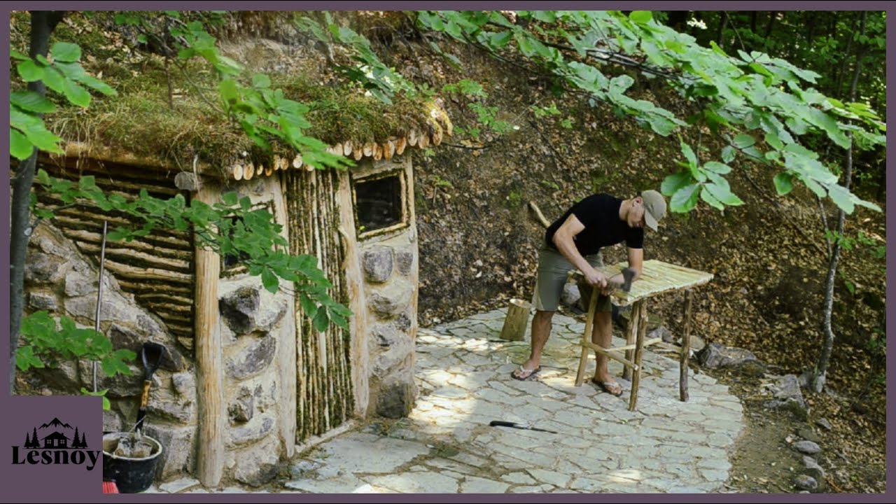 Shelter for survival in the forest. Construction of a house near a stream