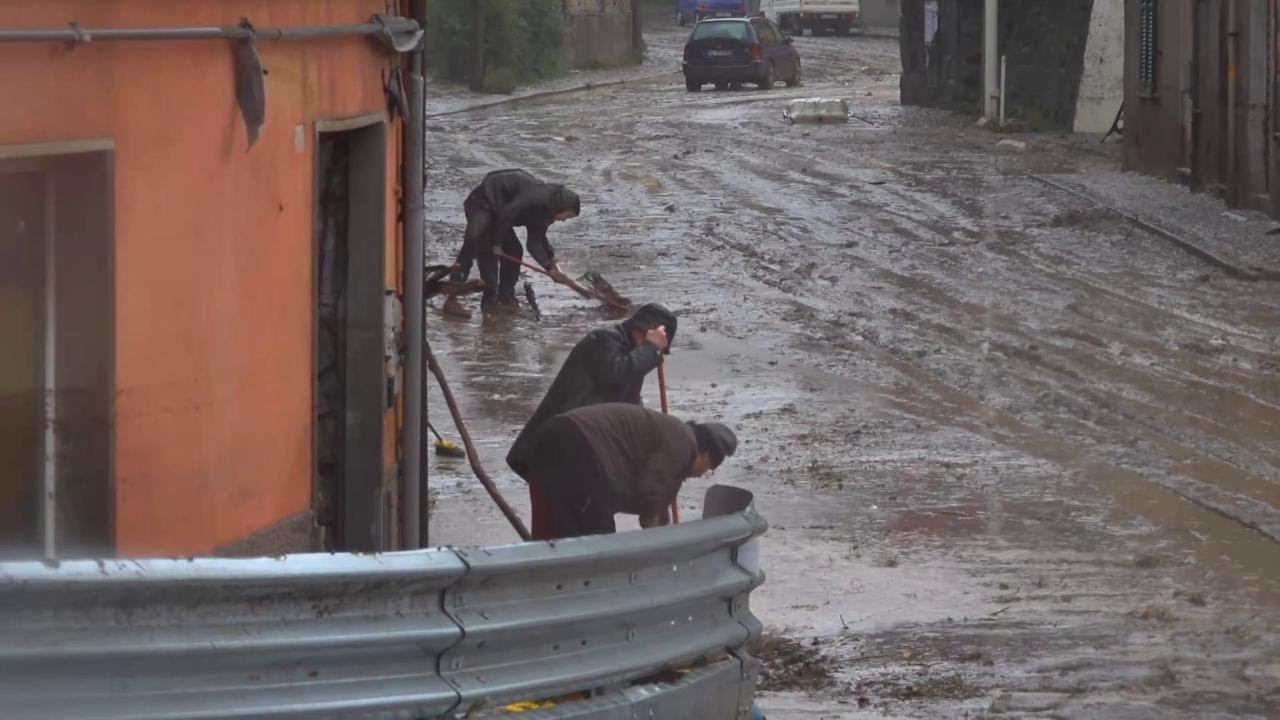Maltempo a Genova: cittadini in strada spalano il fango sotto la pioggia fitta