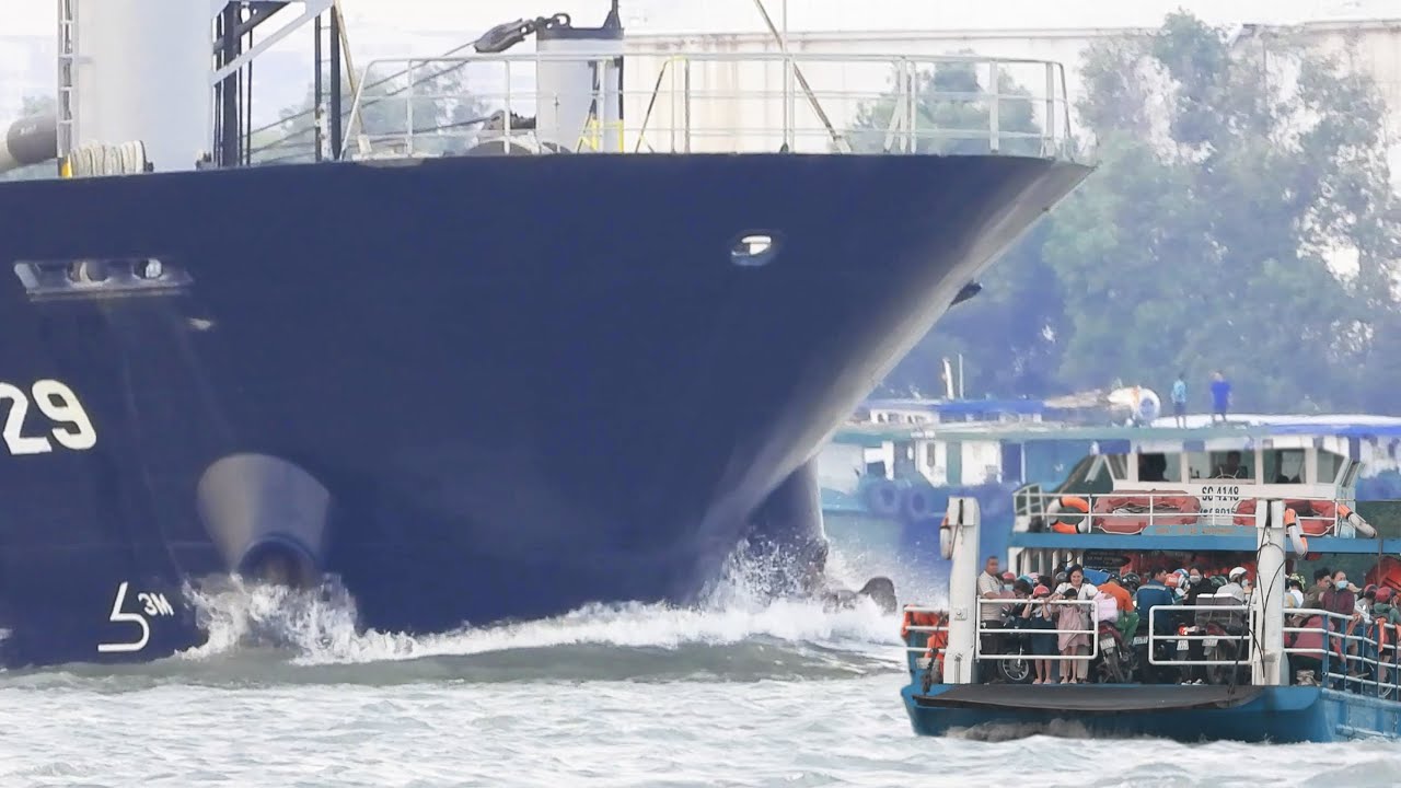 F&auml;hre voller Menschen, die das Gesicht eines Containerschiffs &uuml;berqueren | 4K-Schiffsbeobachtung