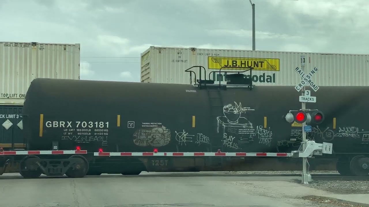 Slow moving tanker train at railroad crossing as  intermodal train passes in opposite direction