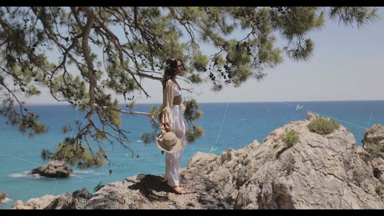 Stylish Woman Overlooks Ocean From Cliffside With Pine Trees In Background