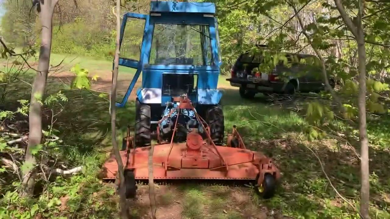 Ford 1210 pulling a broken tree top down.