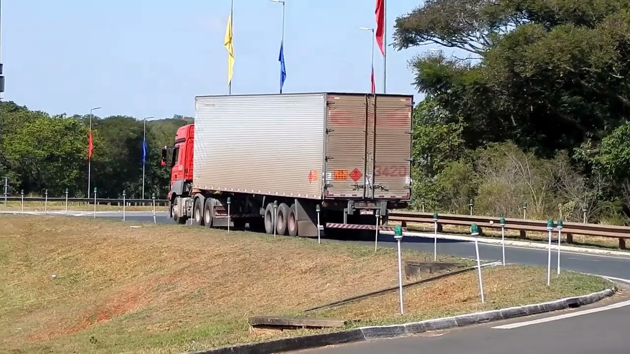 tracteur routier rouge et semi grise 3 essieux qui prends un route en virage